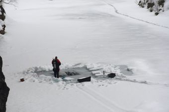 Scuba divers dive into a hole in the ice