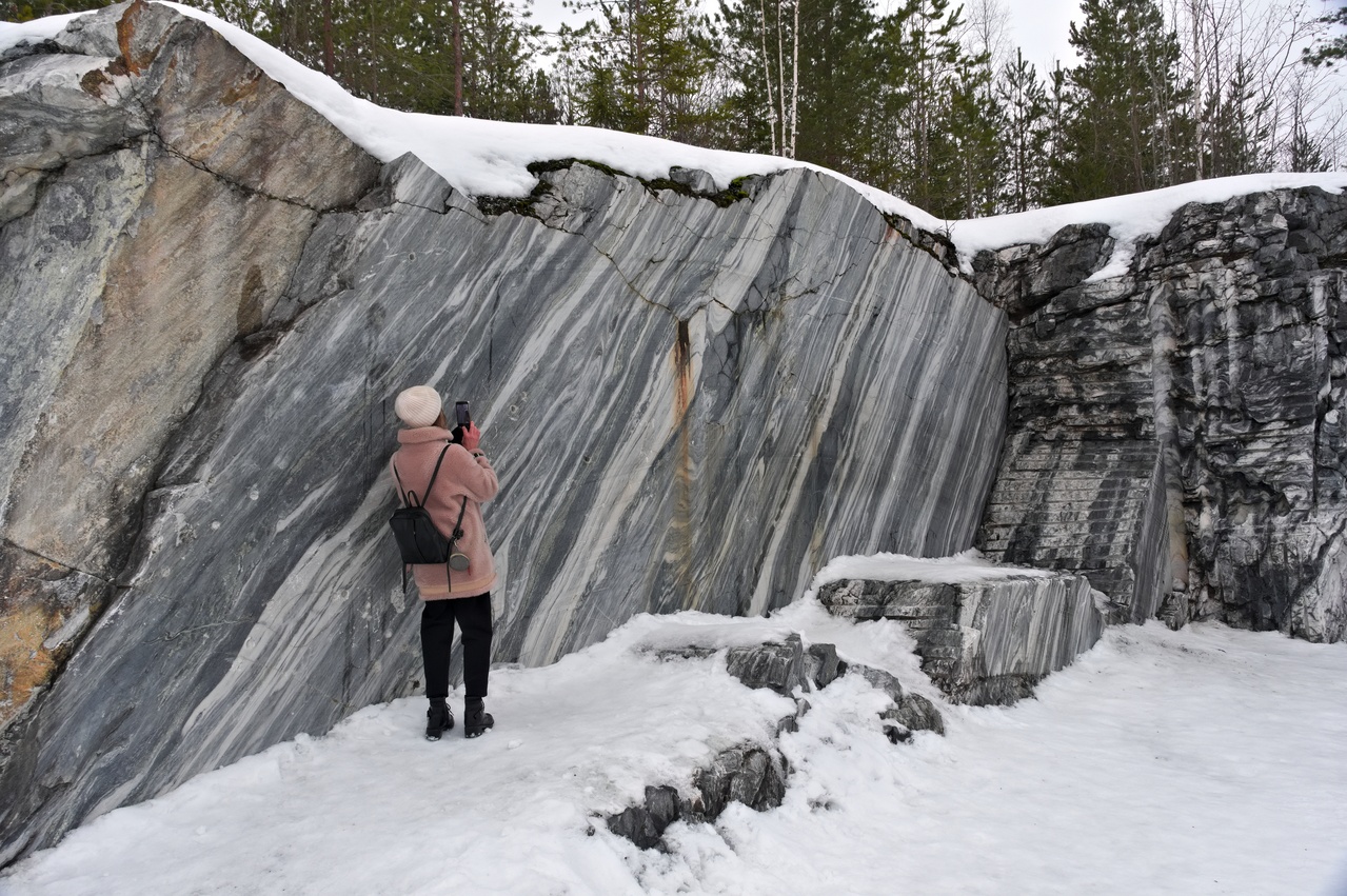 A woman takes a photo near a cliff