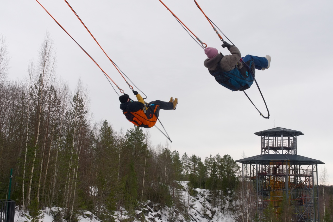 A young couple is swinging very high on a swing