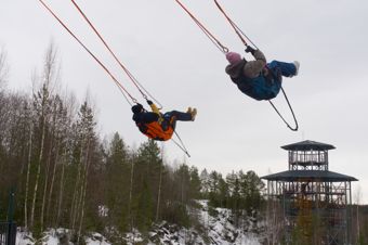 A young couple is swinging very high on a swing